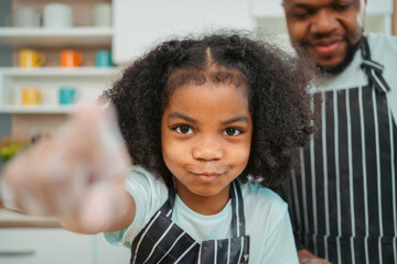 In a home kitchen, black father and his daughter bond over cooking a meal food, their laughter and love filling the air, embodying the joy of African American family life, Father's Day concept - 765031842
