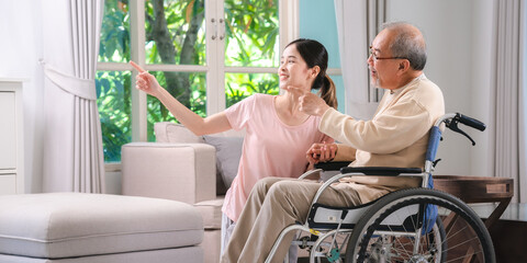 Celebrating Father's Day, Senior Asian grandfather in a wheelchair shares a happy moment at home, hugging his family together, symbolizing generational love and care, health care and life insurance - 765031897