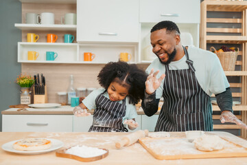 In a home kitchen, black father and his daughter bond over cooking a meal food, their laughter and love filling the air, embodying the joy of African American family life, Father's Day concept - 765031898