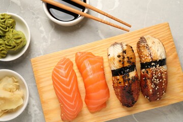 Delicious nigiri sushi, soy sauce, wasabi, ginger and chopsticks on light grey marble table, flat lay