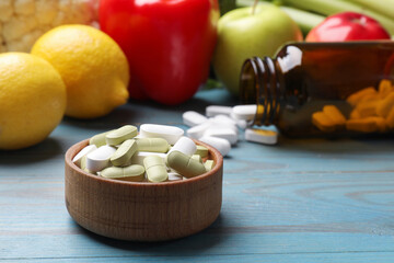 Dietary supplements. Bowl with different pills near food products on light blue wooden table,...