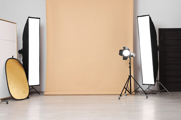Beige photo background and professional lighting equipment in studio