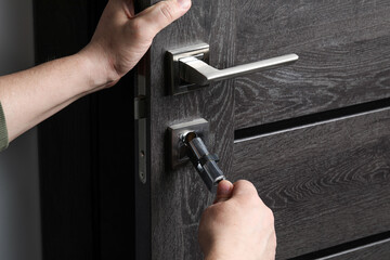 Handyman changing core of door lock indoors, closeup