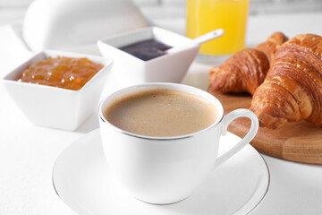 Fresh croissants, jams and coffee on white table, closeup. Tasty breakfast