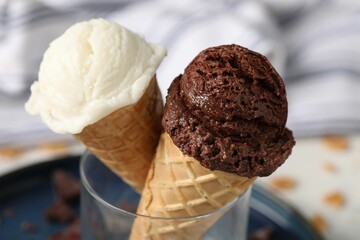 Tasty ice cream scoops in waffle cones on blurred background, closeup