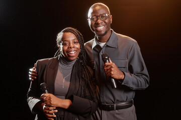 Portrait of two African American performers on stage looking at camera with spotlight - obrazy, fototapety, plakaty