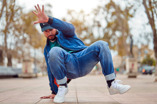 breakdancer guy performing downrock or floor based footwork stunt on the street	
