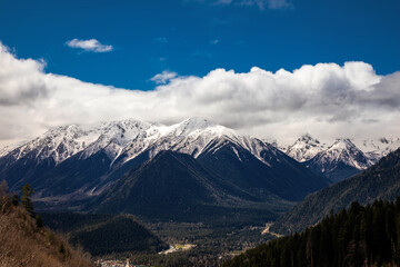 Beautiful mountain landscape. Clouds in the sky. Green grass. Snow on mountain peaks.	