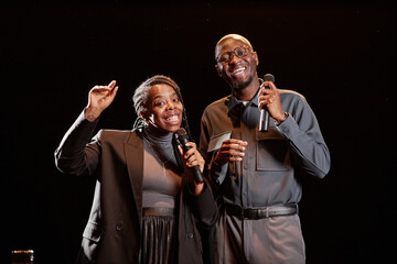 Waist up of entertainers duo on stage speaking to microphone together