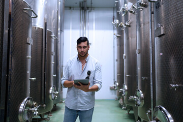 Winemaker working in modern large winery factory liquor drink industry quality and fermentation monitor.