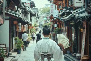 Fototapeten A woman wearing a white kimono walks down a narrow street in a foreign country © mila103