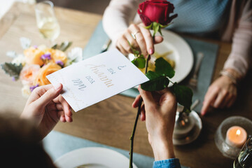Proposing with a red rose at the dinner table - obrazy, fototapety, plakaty