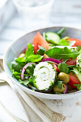 Summer Salad with Cream Cheese, green Olives, Tomatoes and fresh Basil. Bright wooden background. Close up	