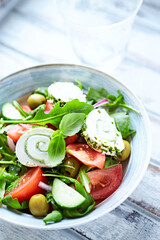 Summer Salad with Cream Cheese, green Olives, Tomatoes and fresh Basil. Bright wooden background. Close up	