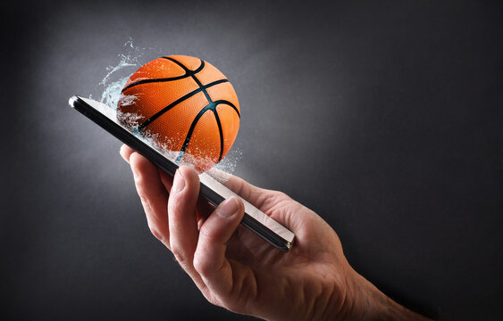 Concept watching basketball online with hand with mobile and ball