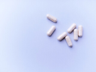 Creatine capsules on bright paper background. Soft focus. Close up. Copy space.	