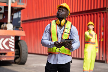Portrait African logistic engineer man worker or foreman working with Asia foreman and forklift container at container site	 - 765060299