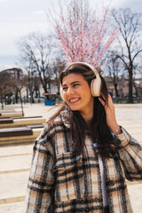 One young girl is listening to music on her wireless headphones and enjoying the sun outdoors	