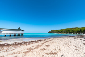 Resort location of white sand beach and turquoise waters of a bay in Antigua and Barbuda with a white dock in the water