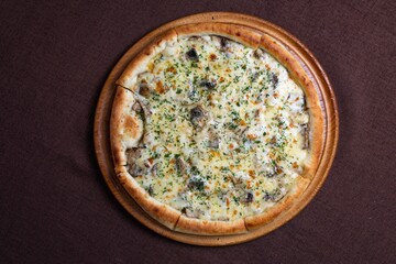 Top view of a delicious pizza with mushrooms and cheese on a wooden board.