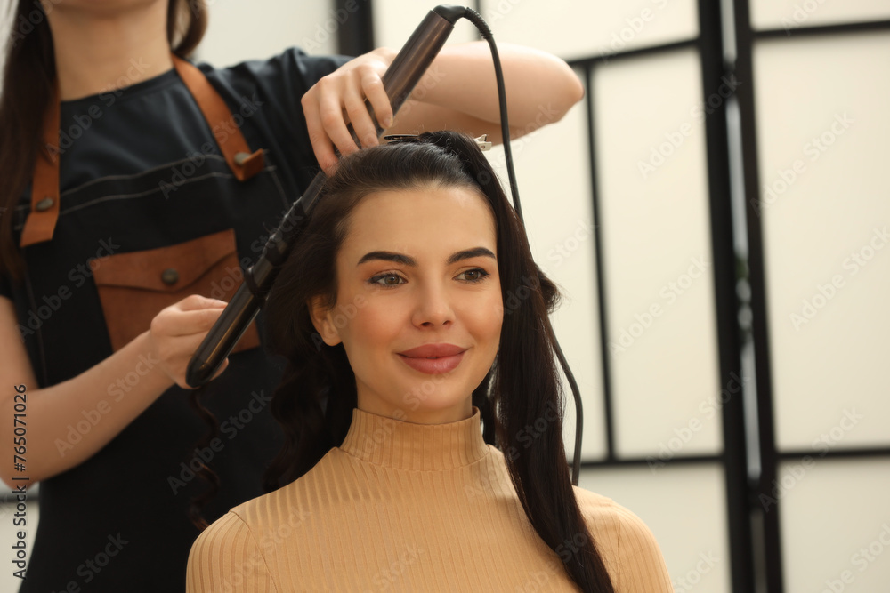 Sticker Hair styling. Hairdresser curling woman's hair in salon, closeup