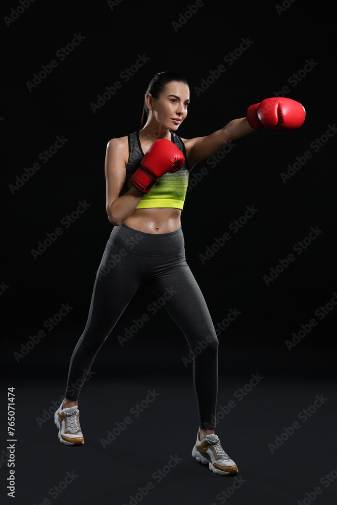 Canvas Prints Beautiful woman in boxing gloves training on black background