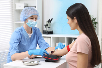 Fototapeta premium Laboratory testing. Doctor taking blood sample from patient at white table in hospital