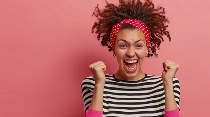After achieving success, a happy young woman with curly hair is celebrating by clenching her fists