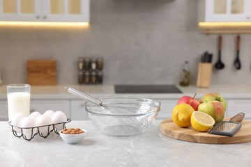Fototapeta na wymiar Metal whisk, bowl, grater and different products on gray marble table in kitchen