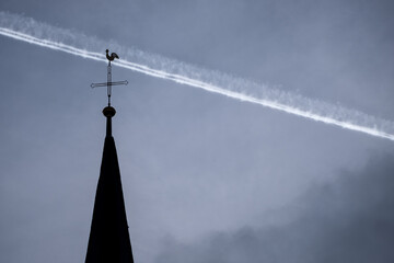 Kirchturmspitze und Kondensstreifen eines Flugzeugs