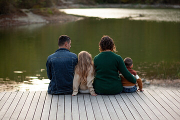 Back view of happy family of four people, mom, dad, daughter and son spend time outside the city on...