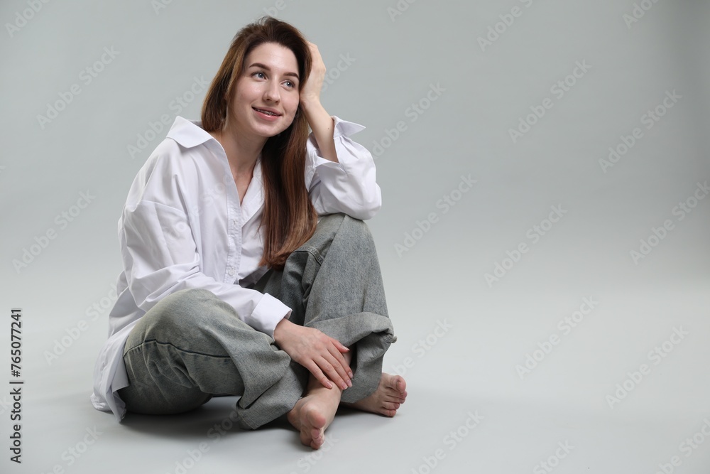 Sticker Portrait of beautiful young woman sitting on grey background, space for text