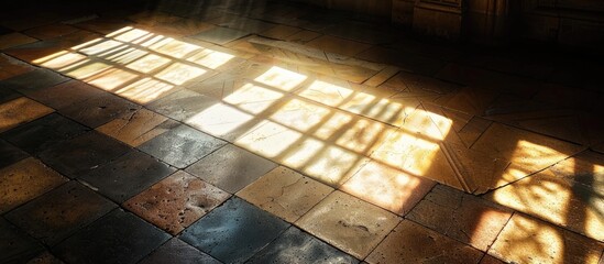 A natural beam of light shining through a window casts a warm glow onto the tiled floor of a church - obrazy, fototapety, plakaty