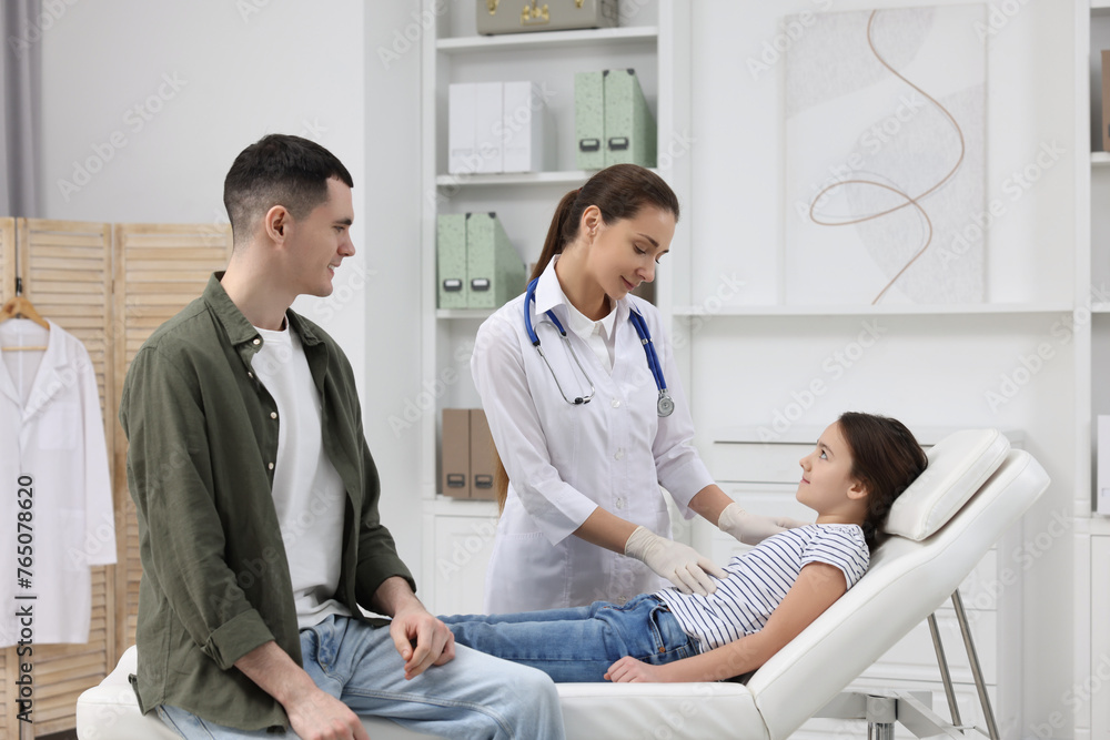 Wall mural Gastroenterologist examining girl with stomach ache on couch in clinic