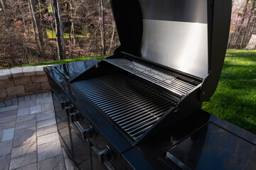 Backyard garden view with a black gas grill in springtime. Outdoors cooking concept.