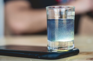 Detailed view of little glass with colorful, swirling and sparkling drink