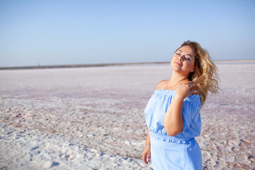 Beautiful plus size woman weared blue dress and walking in the beach against the sea salt