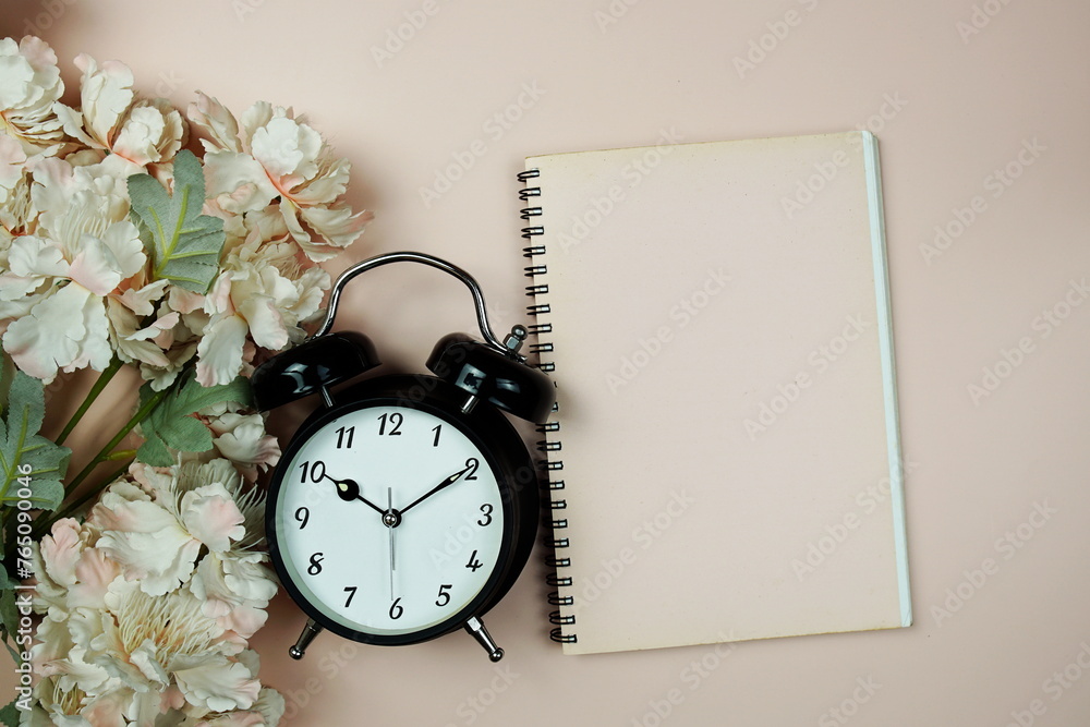 Sticker Empty notebook with alarm clock and flowers top view on pink background