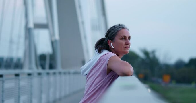 Senior woman jogging on a bridge.