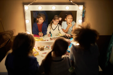 high angle portrait of three little children looking into mirror preparing for theater performers...