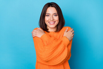Portrait of attractive cheerful girl hugging herself wool clothes wear isolated over vivid blue...