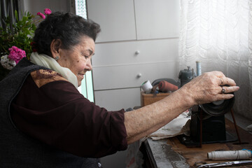 grandmother using traditional sewing machine at home