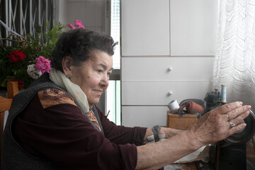 grandmother using traditional sewing machine at home