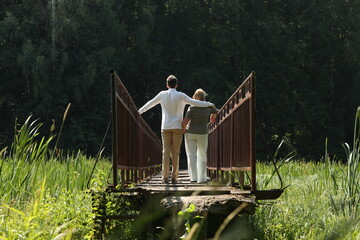 Young adult son in white shirt and his Mother walking on a narrow bridge. Photo was taken 6 July 2023 year. - 765101655