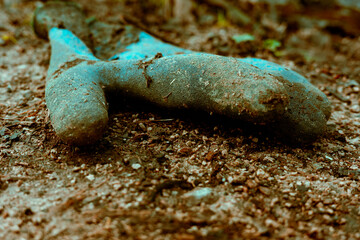rubber protective work glove discarded on the ground dirty and worn