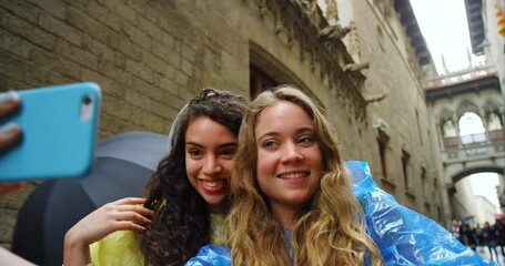 Friends, women and selfie in street, rain and funny face with smile, peace sign and excited for live stream. Group, gen z girl and people with photography, post and social network in Barcelona