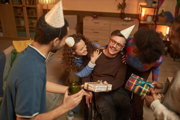 High angle portrait of happy man with disability celebrating Birthday party with group of adult friends at home