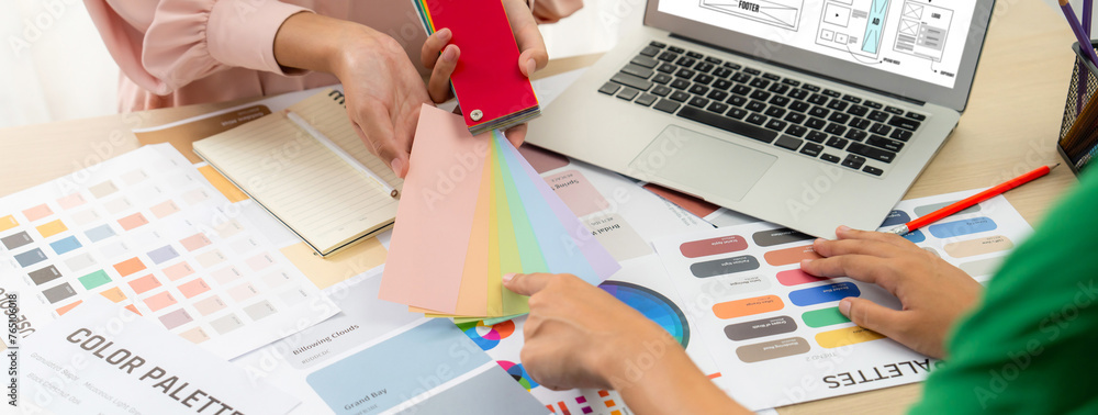 Poster cropped image of interior designer chooses color from color swatches while laptop displayed website 