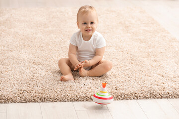 Children toys. Cute little boy and spinning top on rug at home