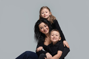 Fototapeta na wymiar Little children with their mother on grey background